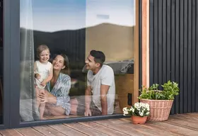 Förderservice Sanierung Familie sitzt zu Hause vor dem Fenster